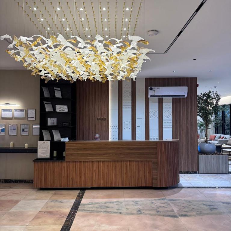 a lobby with a large chandelier above a desk at قصر الرحابة للشقق المخدومة in Hawāyā