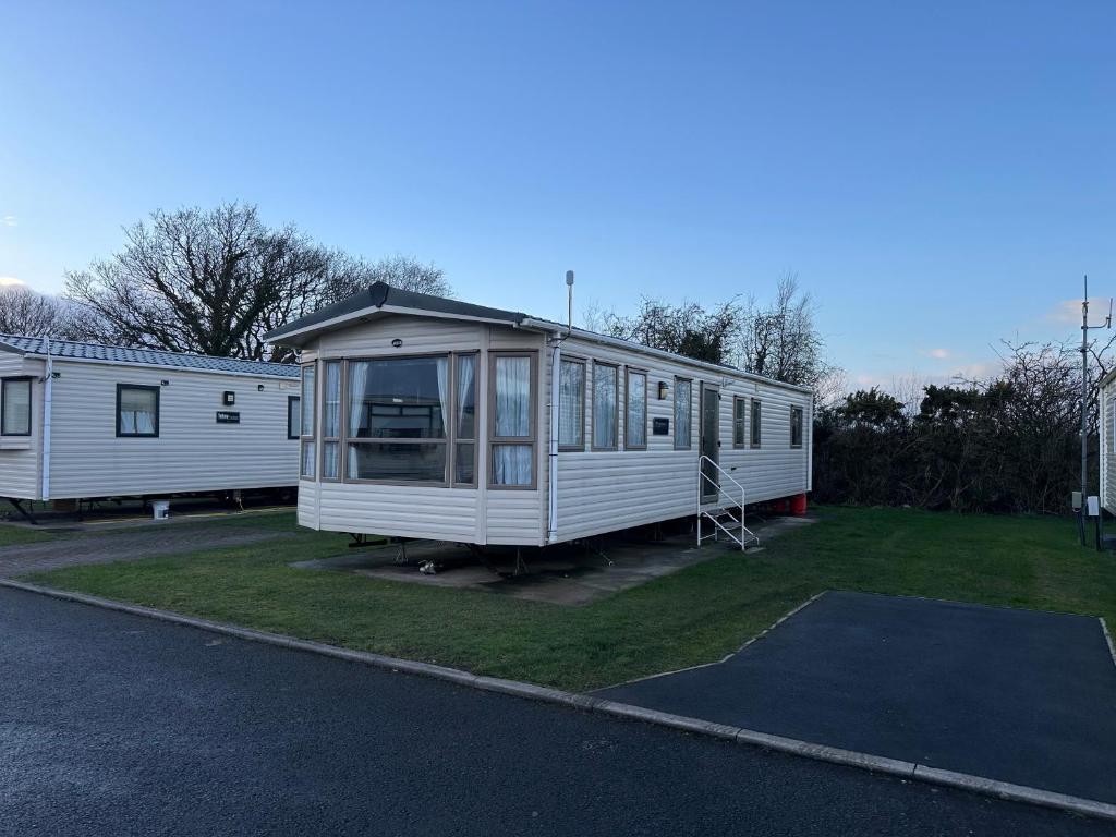 a white mobile home parked in a parking lot at The Cosy Hedgerow in Port Carlisle