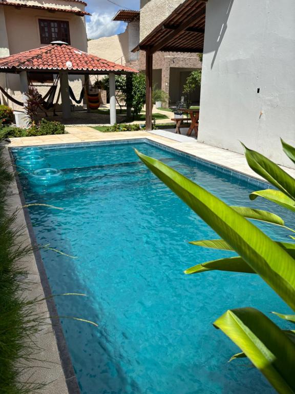 a swimming pool with blue water in front of a house at Pousada Casa Marelle in Paracuru
