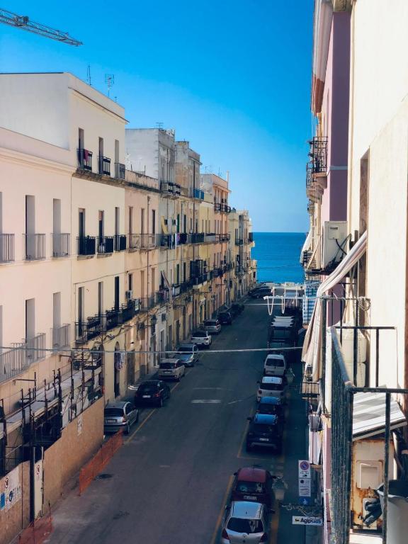 a city street with parked cars and the ocean at Annacare in Trapani
