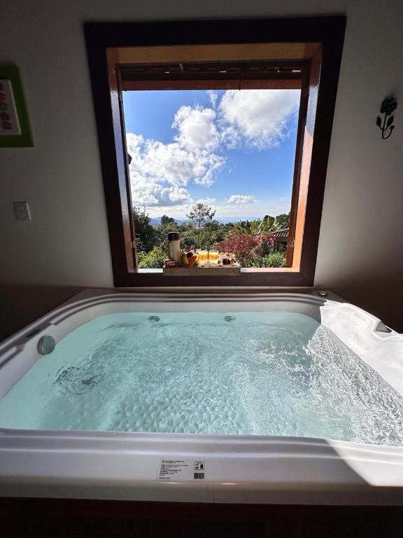 a bath tub with a window in a room at Chalés Lavras de Minas - Brasil in Lavras Novas