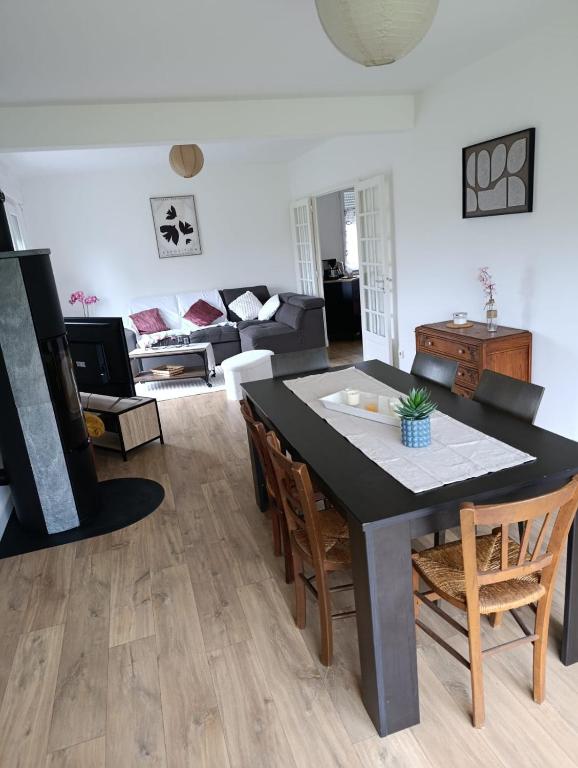 a living room with a black table and chairs at Maison bretonne 119 m2 - jardin clos - 30 min Côte Émeraude in Plénée-Jugon
