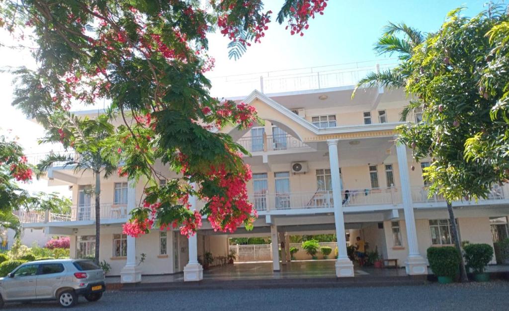 a large white building with trees in front of it at Studio without kitchen at Alpha Villa in Flic-en-Flac