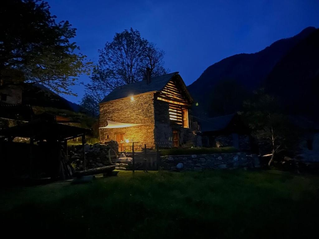 a small stone building at night with the lights on at Rustico La Stalla a Pianezza in Menzonio
