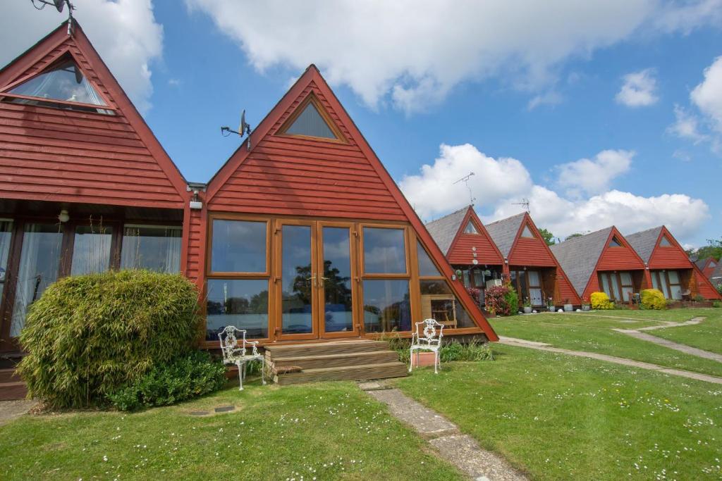 a house with a red roof with two chairs in the yard at Chalet Seventyfour in Deal