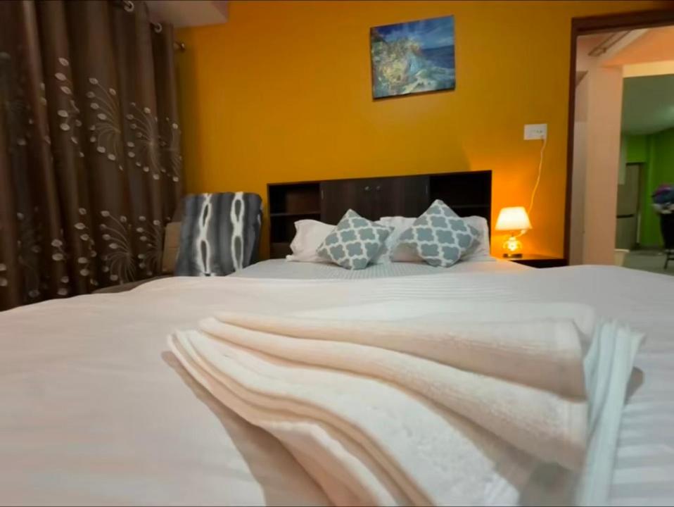 a bedroom with a large white bed with blue pillows at Qeva Apartment I in Kathmandu