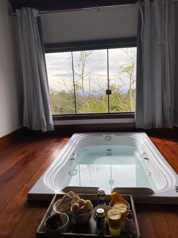 a bath tub in a room with a large window at Chalés Lavras de Minas - Canadá in Lavras Novas