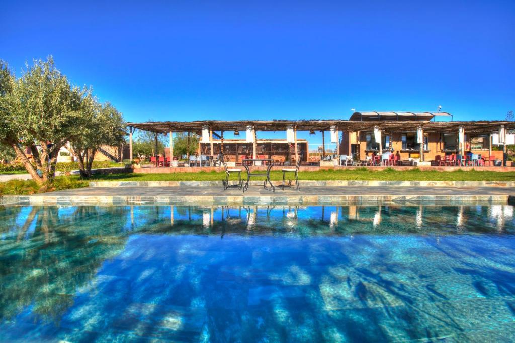 Ein großes Wasserbecken mit einem Gebäude im Hintergrund in der Unterkunft The Ranch Resort in Marrakesch
