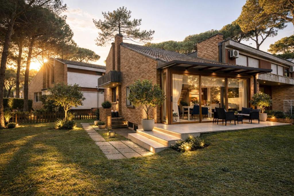 a house with glass doors and a patio at Villa Pineta Grande in Lignano Sabbiadoro