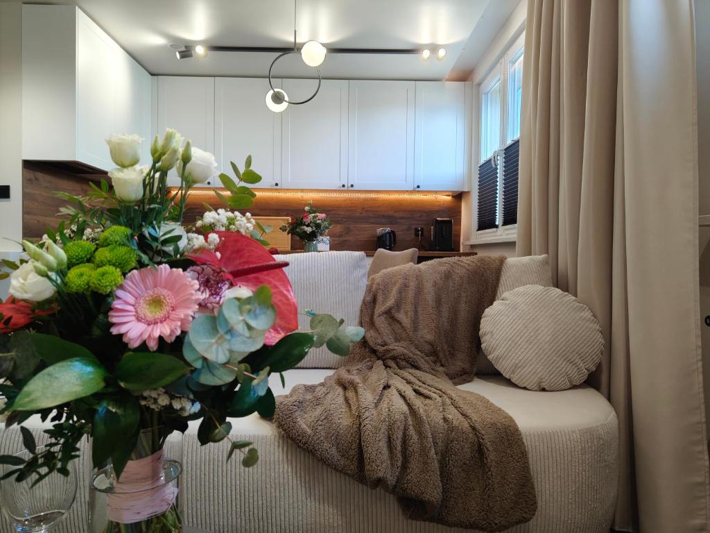a living room with a couch and a vase of flowers at Studio 27 in Zabrze