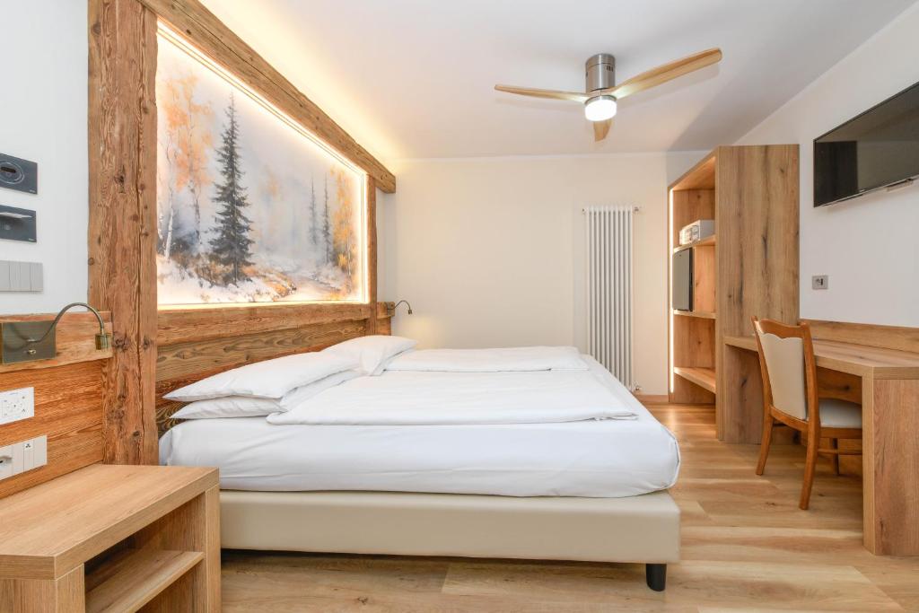 a bedroom with a bed and a desk and a table at Hotel Denny in Pinzolo