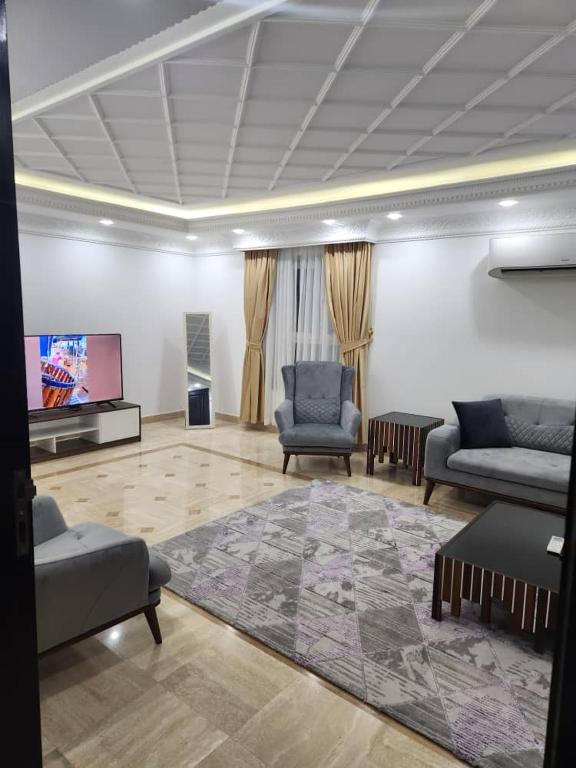 a living room with two chairs and a flat screen tv at Shahan Residence in Muscat