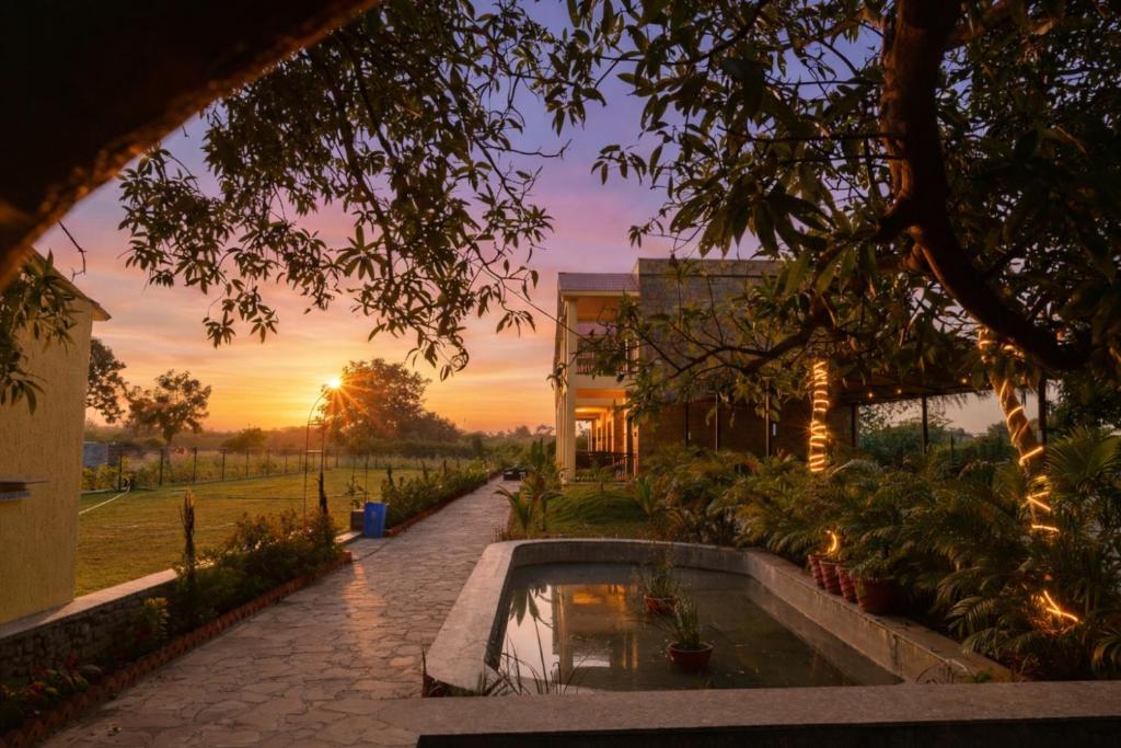 a pool in a garden with a sunset in the background at Achal Bagh - Boutique Stay Abu Road in Māwāl