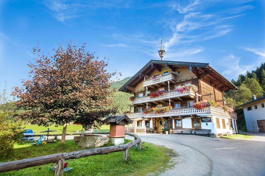 a large wooden house with a fence in front of it at Hauserhof- Urlaub am Bauernhof inklusive Sommercard in Bramberg am Wildkogel