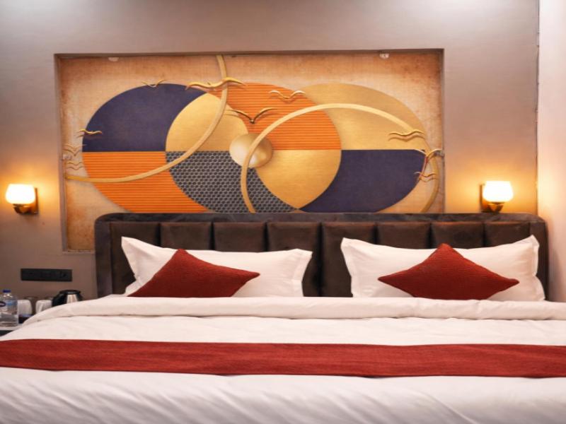 a bedroom with a large bed with red pillows at Royal Milestone Resort & Hotel in Gwalior