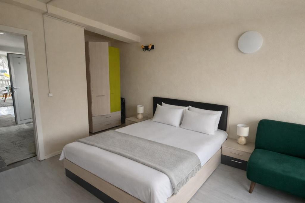 a bedroom with a bed and a green chair at Апартамент Зора in Chepelare