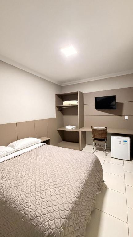 a bedroom with a white bed and a television at Imbau Palace Hotel in Imbau