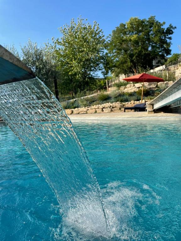 a water fountain in the middle of a pool at Hôtel restaurant Clos des Sullys in Montclus