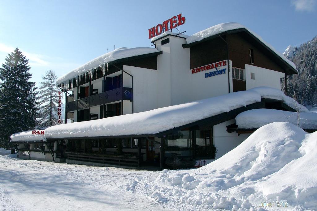 um edifício coberto de neve com um telhado coberto de neve em Hotel Davost em Forni di Sopra