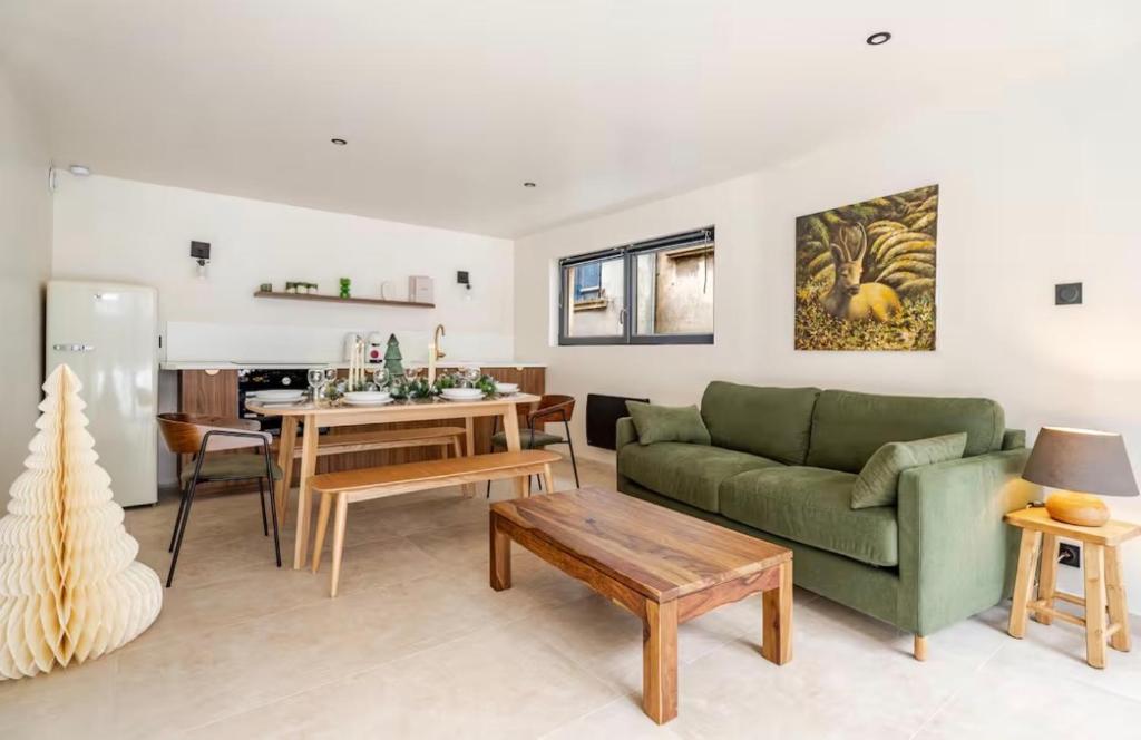 a living room with a green couch and a table at Le JoliCoeur Parking gratuit Idéal cyclistes Proche Alpe d Huez in Le Bourg-dʼOisans