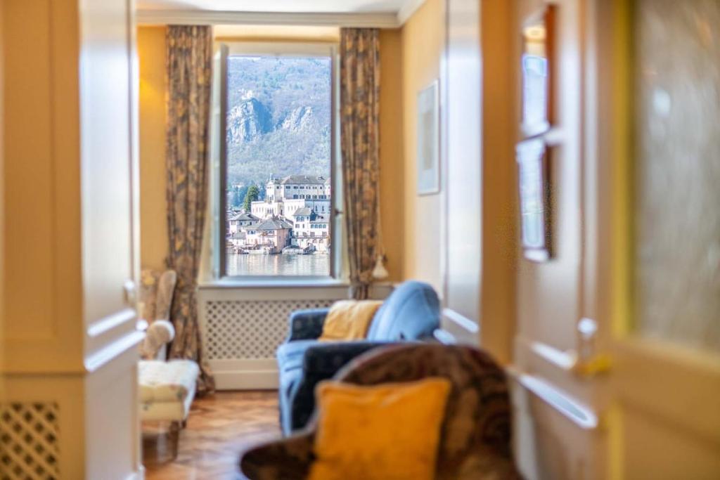 a living room with a blue chair and a window at Casa Orta appartamento con vista lago in Orta San Giulio