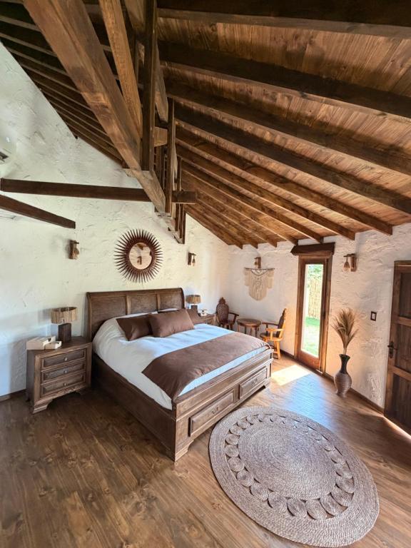 a bedroom with a large bed and a wooden ceiling at Antu Wellness cabaña de lujo en paine in Maipo