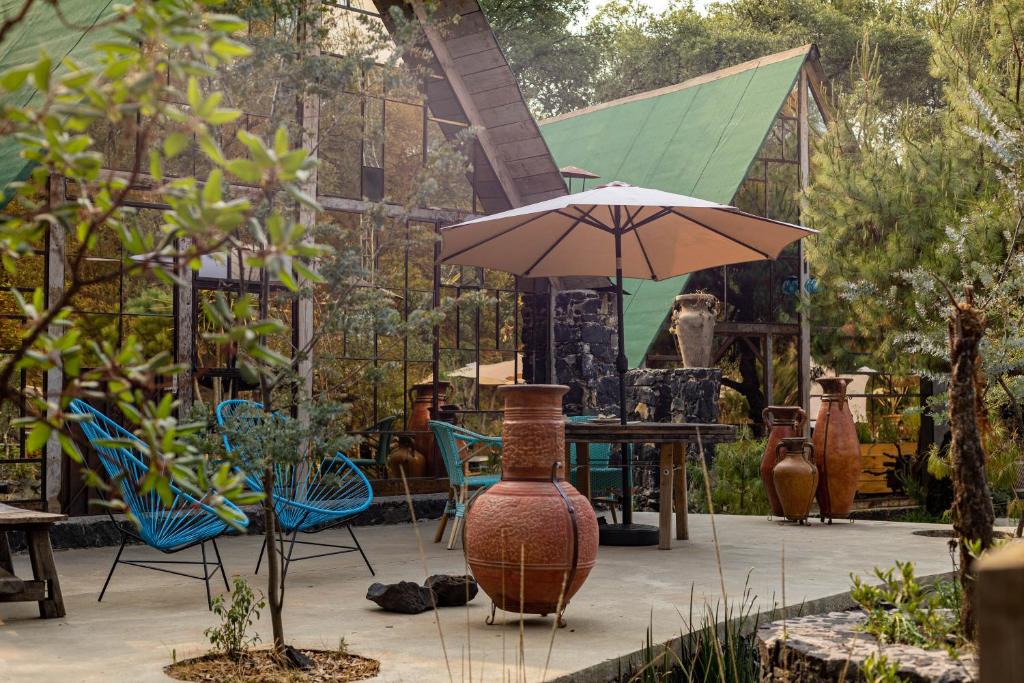 a patio with a table and chairs and an umbrella at Cabaña Romántica, glamping Piedra Braza Orígenes in Ocoyoacac