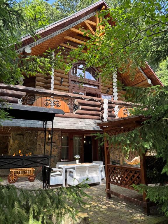 a house with a table and a bench in front of it at Бистриця in Chynadiyovo