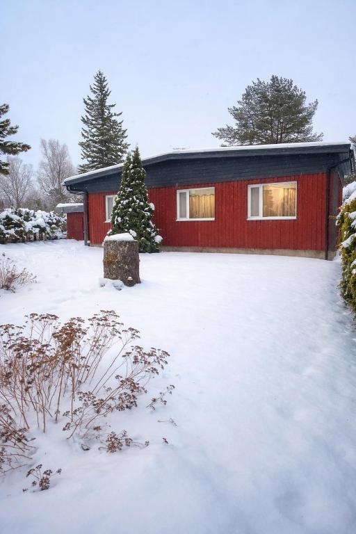 a red house with snow in front of it at Puhkepesa 6 in Otepää