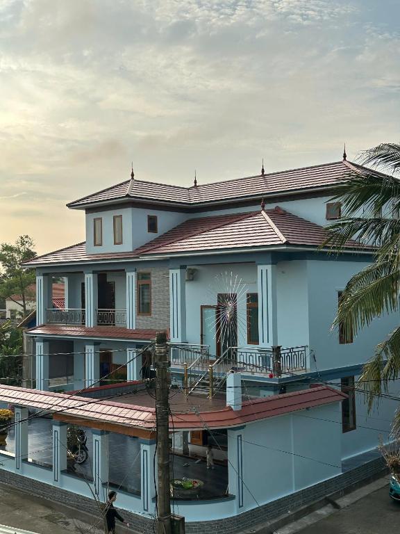 a large house with a porch and a man walking in front of it at Memory Homestay Ông Chung in Lệ Thủy