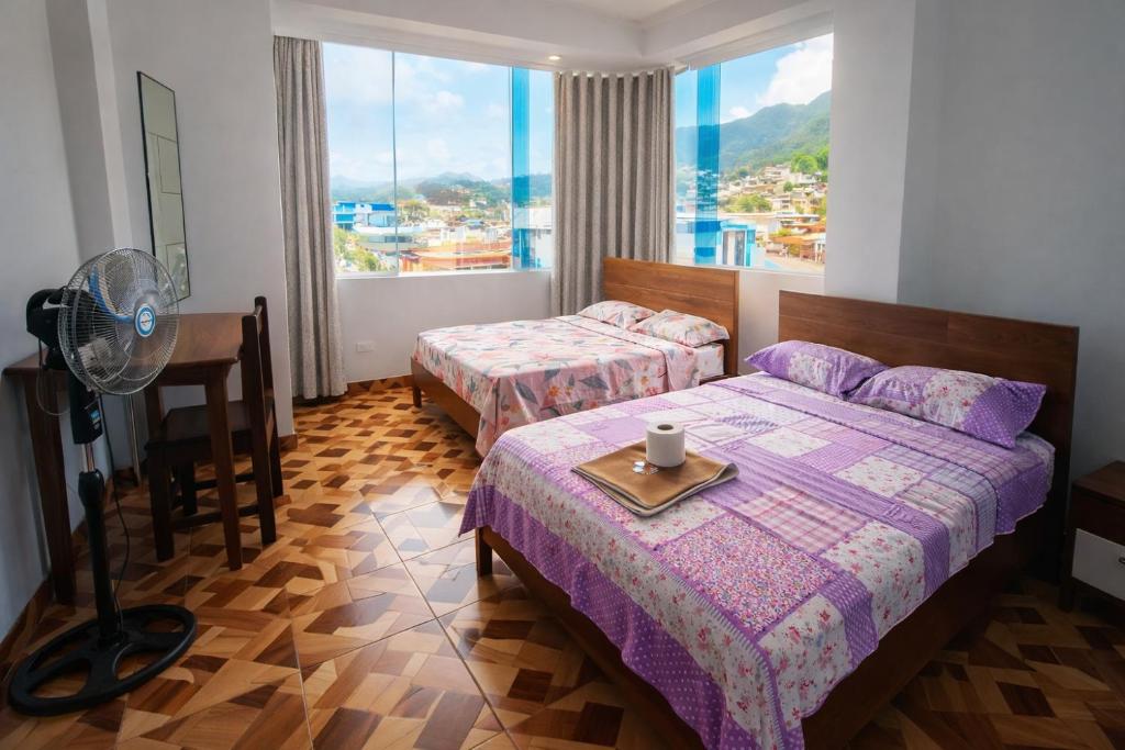 a bedroom with two beds and a fan and a window at HOSPEDAJE EL CANTARO II in Tingo María