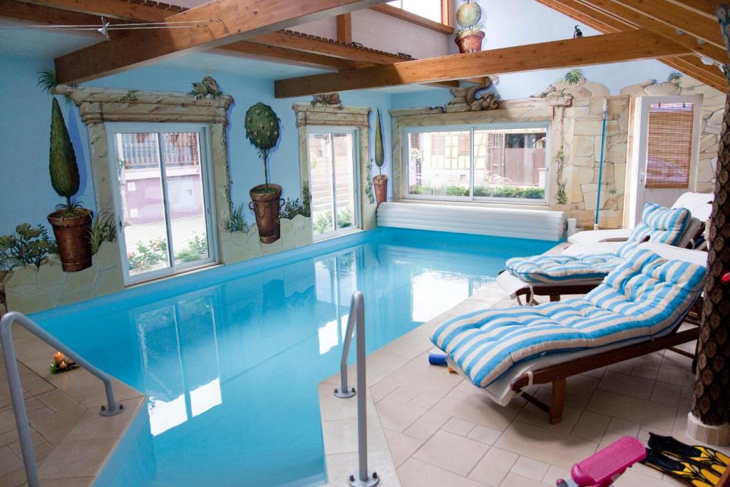 una piscina en una casa con paredes y ventanas azules en A l'étoile d'or, en Batzendorf