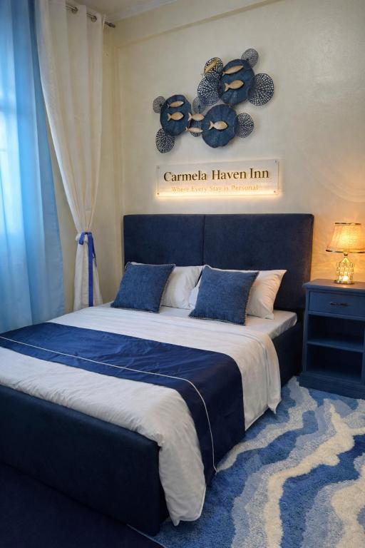 a bedroom with a large bed with a blue comforter at Carmela Haven Inn in Baler