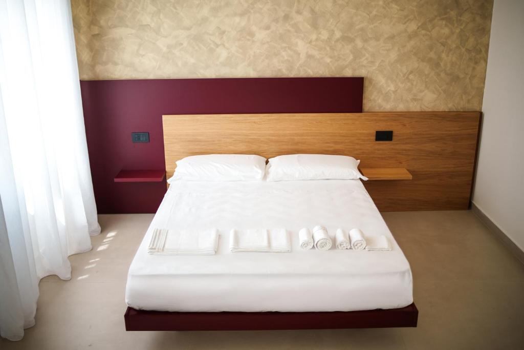 a bedroom with a white bed with a wooden headboard at La Casa di Hera in Crotone