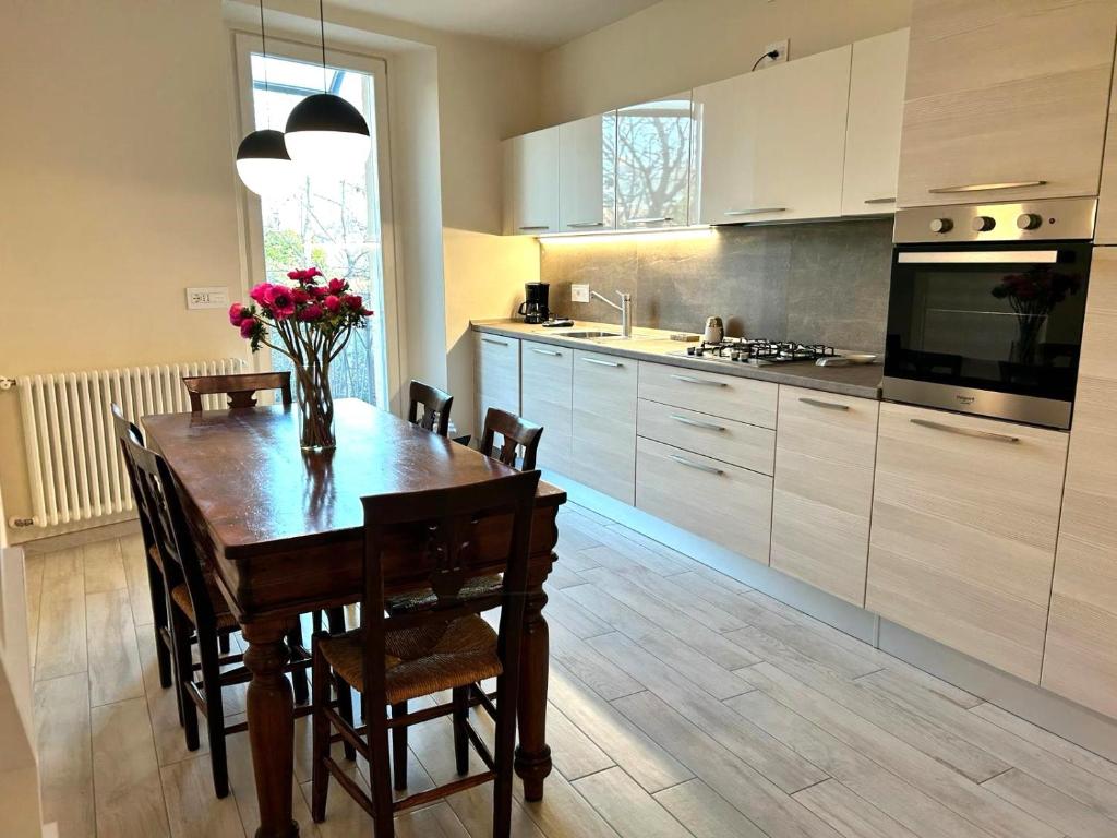 a kitchen with a wooden table with flowers on it at Casa Piccolo Charme e Design nel cuore di Maderno in Toscolano Maderno
