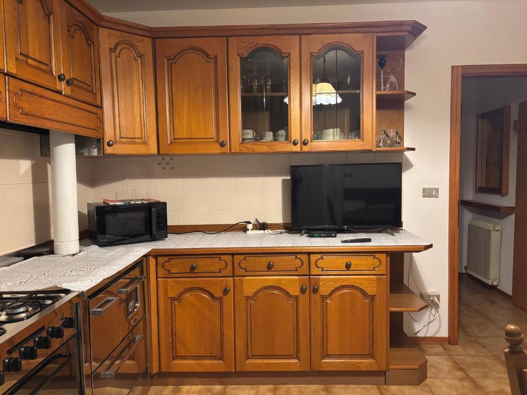 a kitchen with wooden cabinets and a flat screen tv at Casa Monte Agaro in Castello Tesino