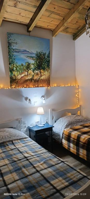 a bedroom with two beds and a painting on the wall at Rizaki Cottage in Nafpaktos in Nafpaktos