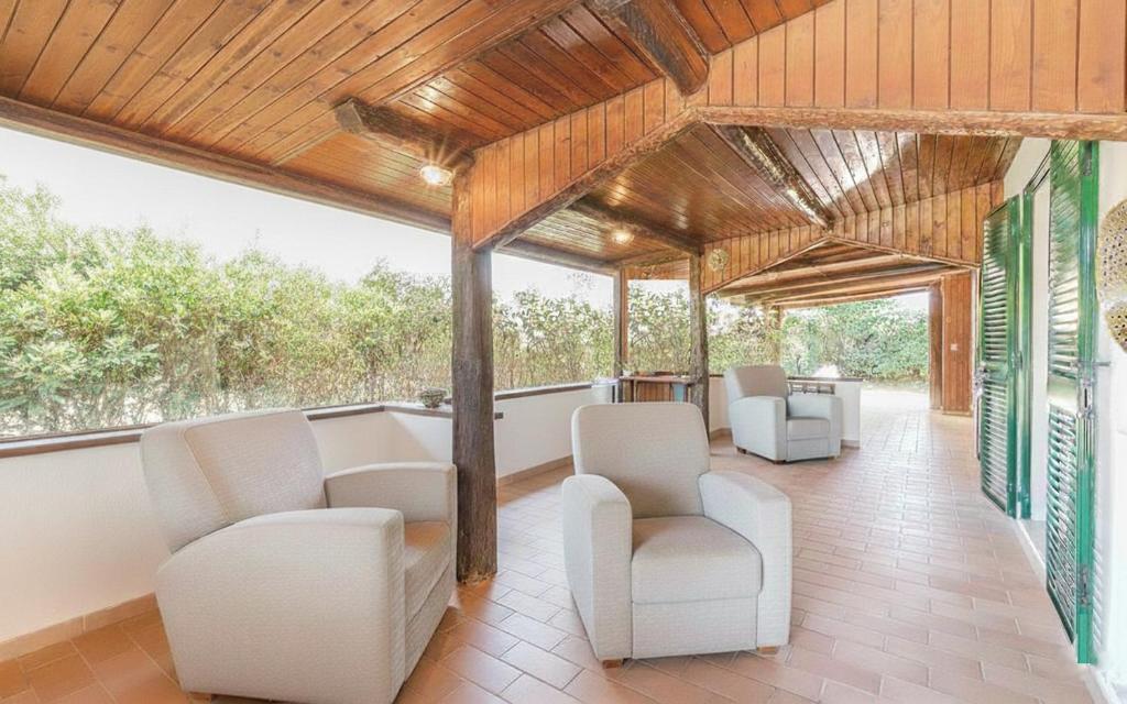 a living room with white chairs and a porch at Villa Cambretta con giardino, posto auto e a due passi dal mare in Giannella