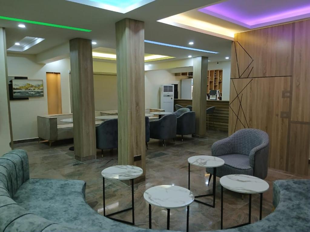 a waiting room with couches and tables and chairs at Stallion Luxury Suites in Ado