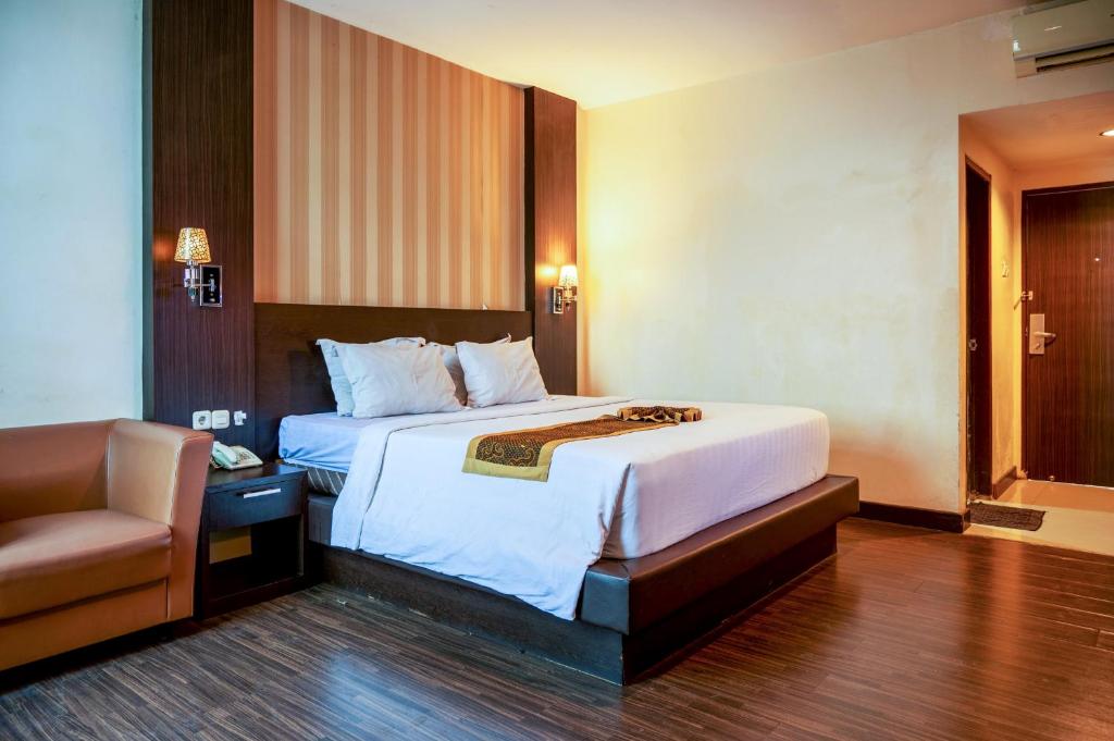 a hotel room with a bed and a chair at Tripletree Stefani Hotel in Pekanbaru