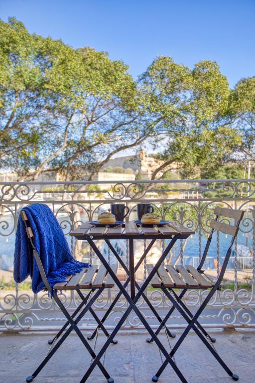 a table with a blue blanket sitting on top at Valletta Marina View - Seafront Apartment in Tal-Pietà