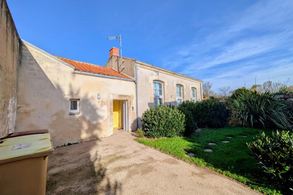 a white house with a yellow door in a yard at Spacious duplex house in Grosbreuil in Grosbreuil