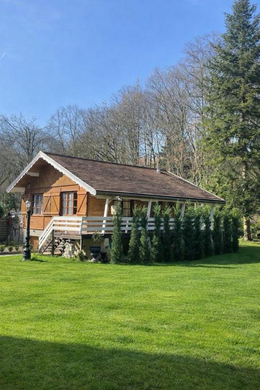 a wooden house with a yard with a yard at Auvers Wood lodge in Auvers-sur-Oise