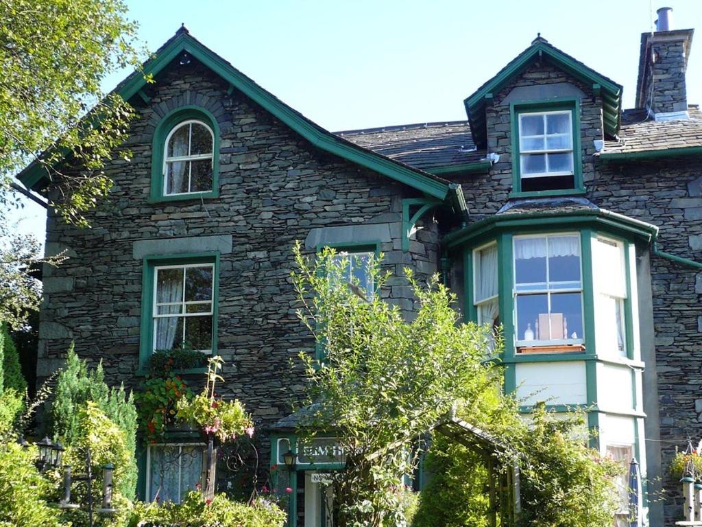 a brick house with green and white windows at Elim House in Bowness-on-Windermere