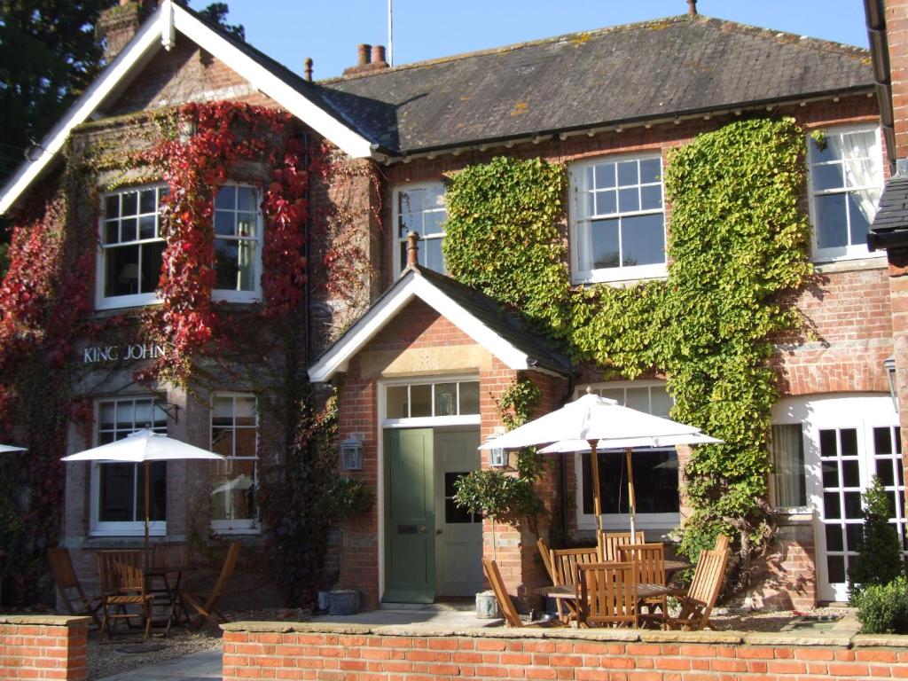 a building with chairs and umbrellas in front of it at King John Inn in Tollard Royal