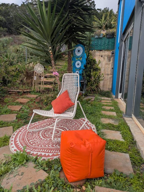a white chair with two red pillows and a bag at Personal blue house Madeira in Santa Cruz
