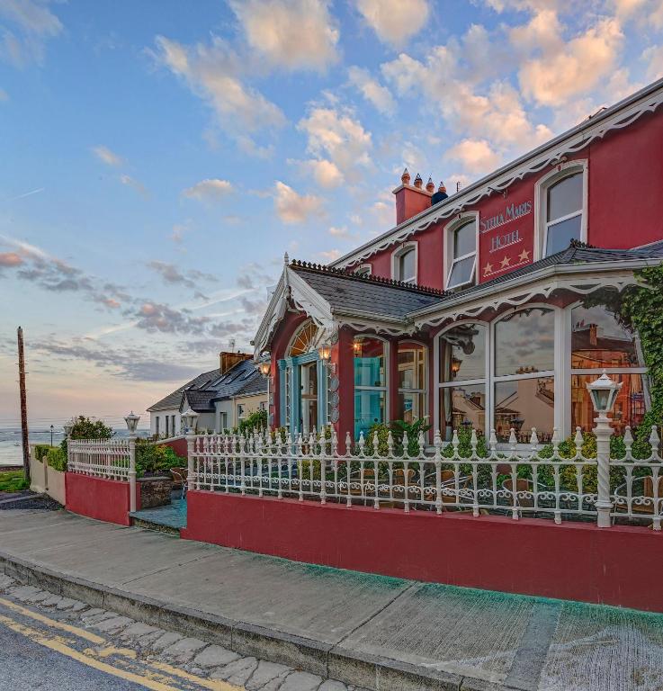 a red house with a white fence on a street at Stella Maris Hotel in Kilkee