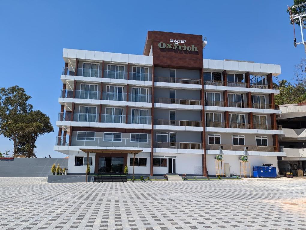 a large white building with a sign on it at Oxyrich Business Class Hotel in Madikeri