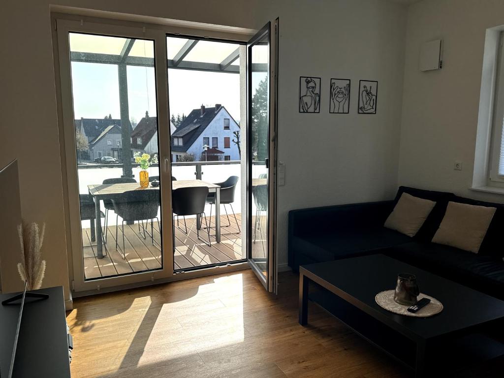 a living room with a couch and a balcony with a table at Apartment Landblick in Bohmte