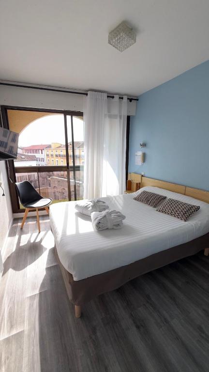a bedroom with a bed and a chair and a window at Hotel Bains Sarrailh in Dax